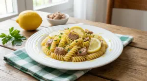 Piatto di pasta con tonno, fette di limone e prezzemolo su un tavolo di legno